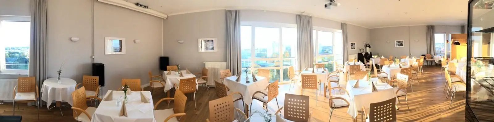 Heller Caféraum mit eingedeckten Tischen, großen Fenstern und Blick über Potsdam.